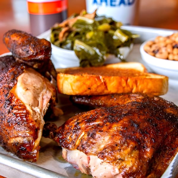 Adam's Rib Co. BBQ chicken with collard greens, baked beans, and Texas toast on a tray.