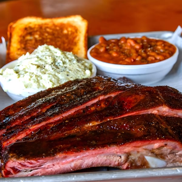 Adam's Rib Co. BBQ ribs with baked beans, coleslaw, and Texas toast on a metal tray.